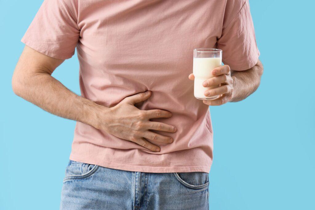 Mann mit Bauchschmerzen und Glas Milch